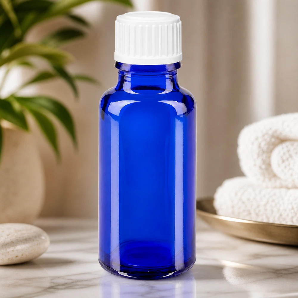 Blå 20 ml apoteksflaska i glas med vit droppkork på marmorunderlägg