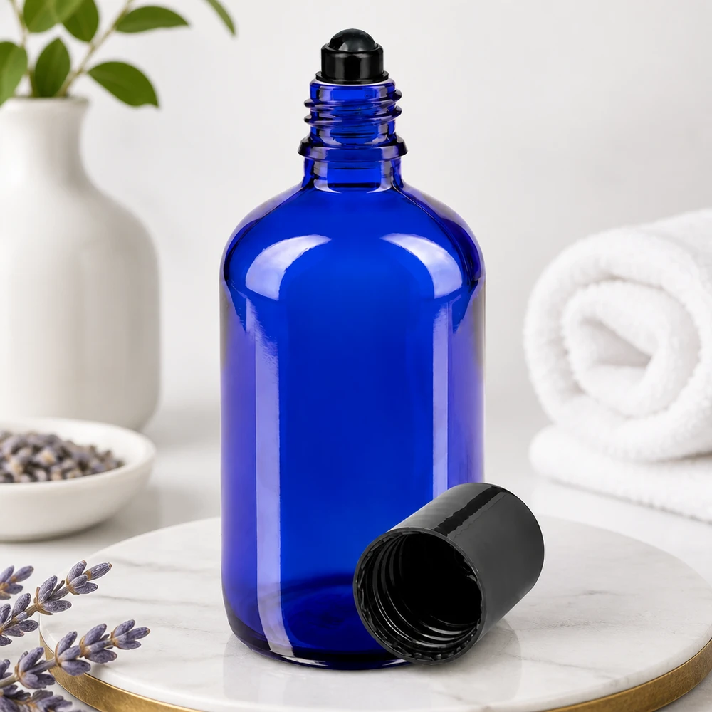 Apoteksflaska blå 100ml roll-on lock svart Blå glasflaska på 100 ml med svart rullkula och avtaget lock på marmor