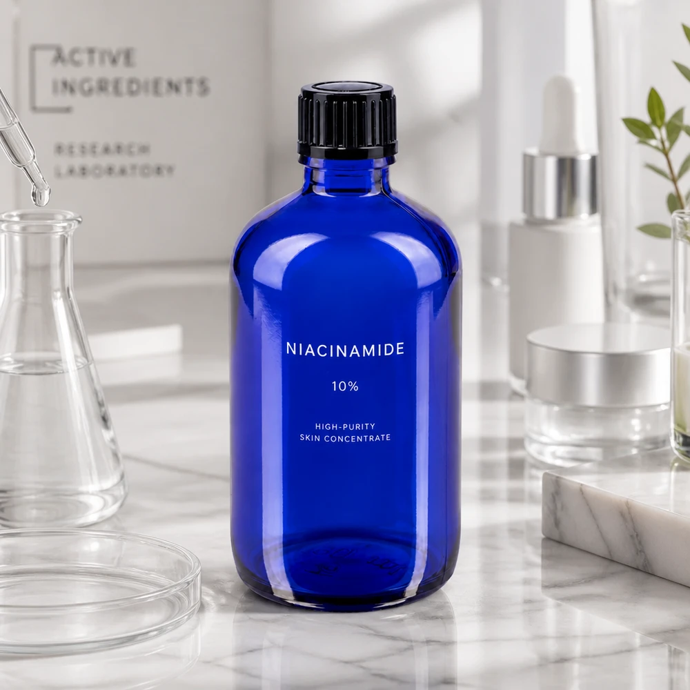 Apoteksflaska blå 100ml dropplock 1mm svart standard Koboltblå apotekarflaska på 100 ml med en etikett med texten ”Niacinamide” på en marmoryta i en laboratoriemiljö