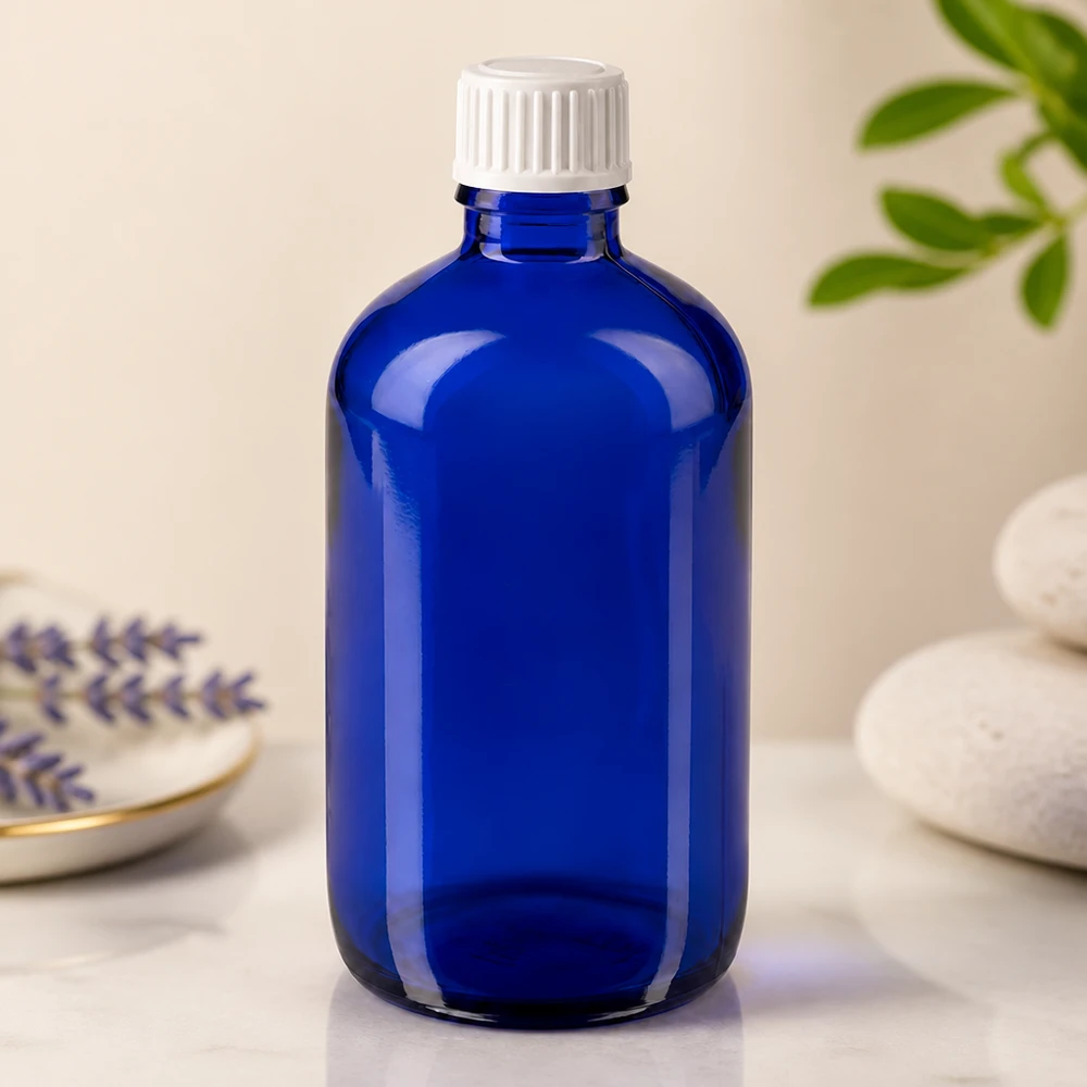 Apoteksflaska blå 100ml skruvkork vit standard Blå glasflaska på 100 ml med vitt barnsäkert lock på en marmoryta bredvid lavendel