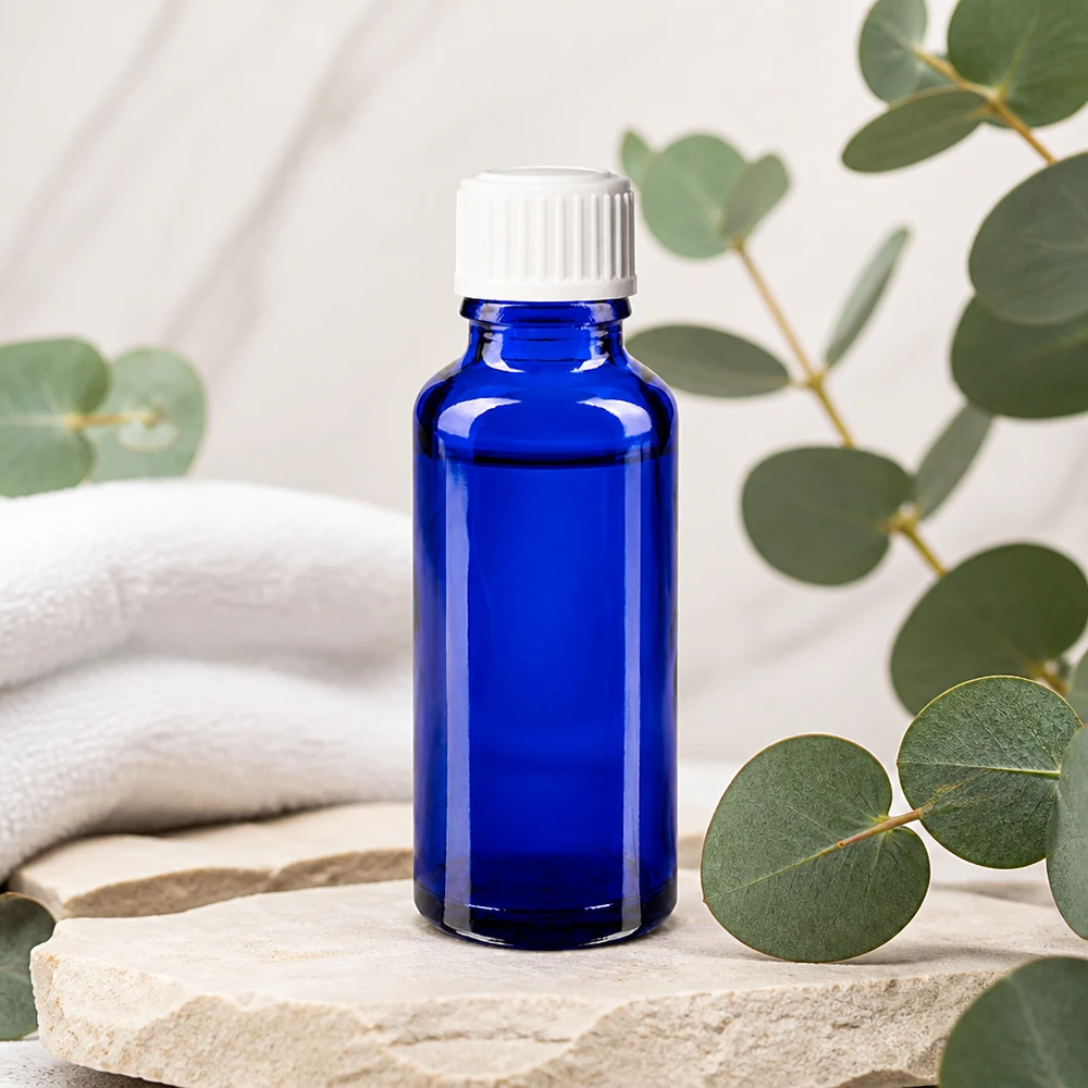 Apoteksflaska blå 30ml skruvkork vit standard Koboltblå 30 ml apoteksflaska med vit droppkork på natursten med eukalyptus
