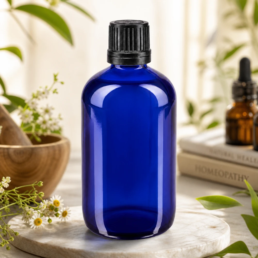 Apoteksflaska blå 100ml skruvkork svart hällring manipulationsskyddad förslutning Blå apotekerglasflaska på 100 ml med räfflad svart kork, omgiven av kamomillblommor och medicinalväxter