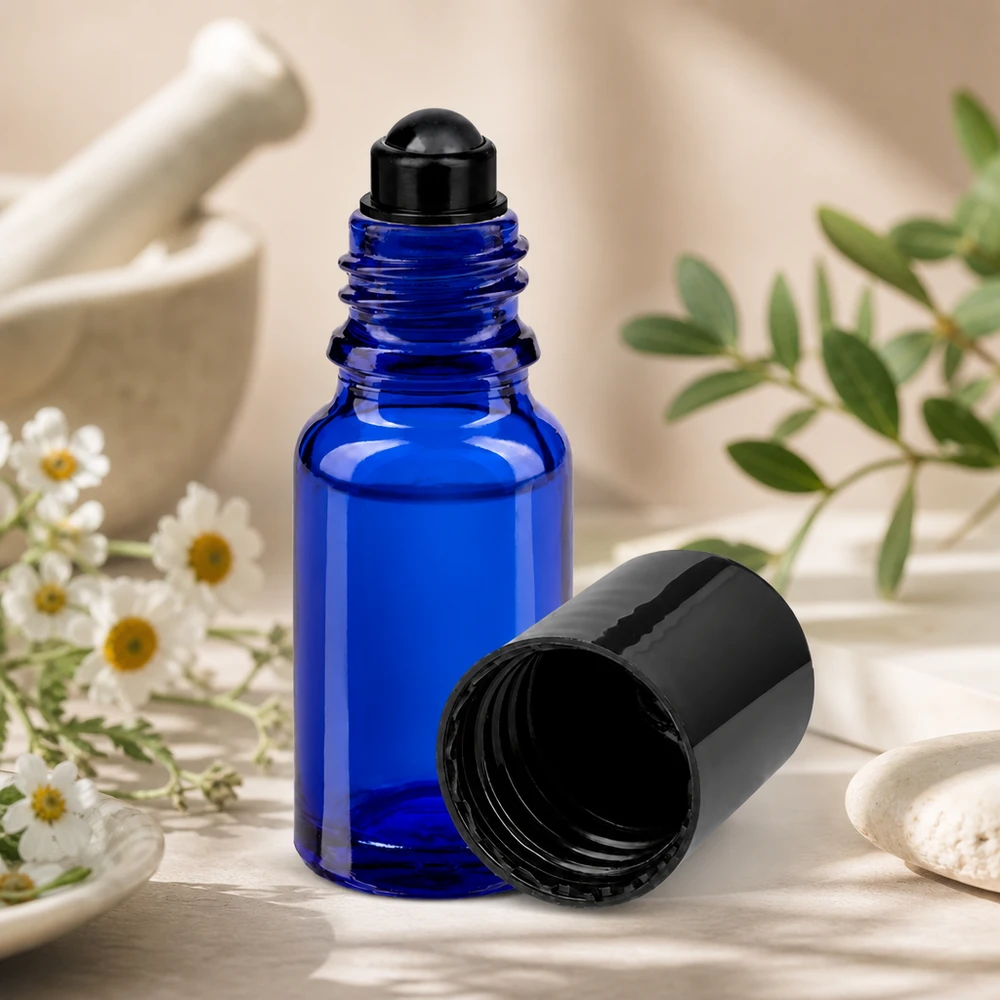 Apoteksflaska blå 10ml roll-on lock svart Blå 10 ml roll-on-flaska STD med svart lock bredvid mortelört och kamomillblommor