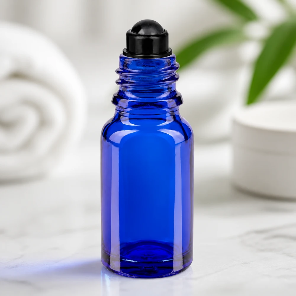Apoteksflaska blå 10ml roll-on lock svart Blå glasflaska på 10 ml med svart roll-on-huvud på marmor mot vit bakgrund