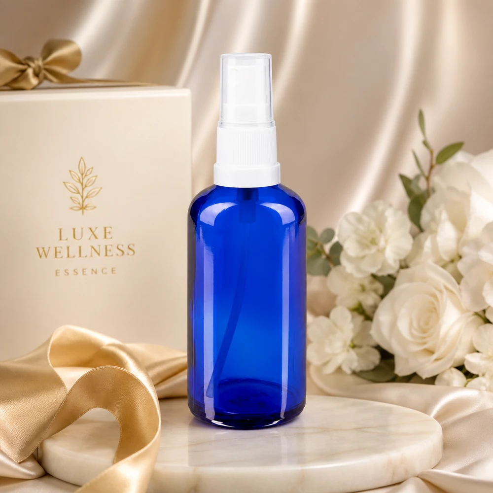 Apoteksflaska blå 50ml spray topp vit En koboltblå glasflaska på 50 ml med vitt spruthuvud mot en elegant presentförpackning i bakgrunden
