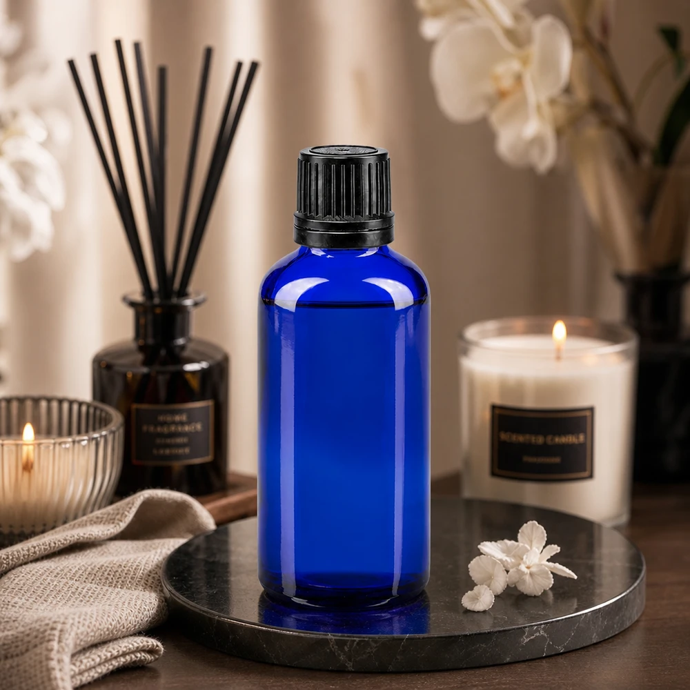 Apoteksflaska blå 50ml skruvkork svart hällring manipuleringssäker förslutning 50 ml blå glasflaska med svart skruvlock på ett marmorfat med ljus och doftljus