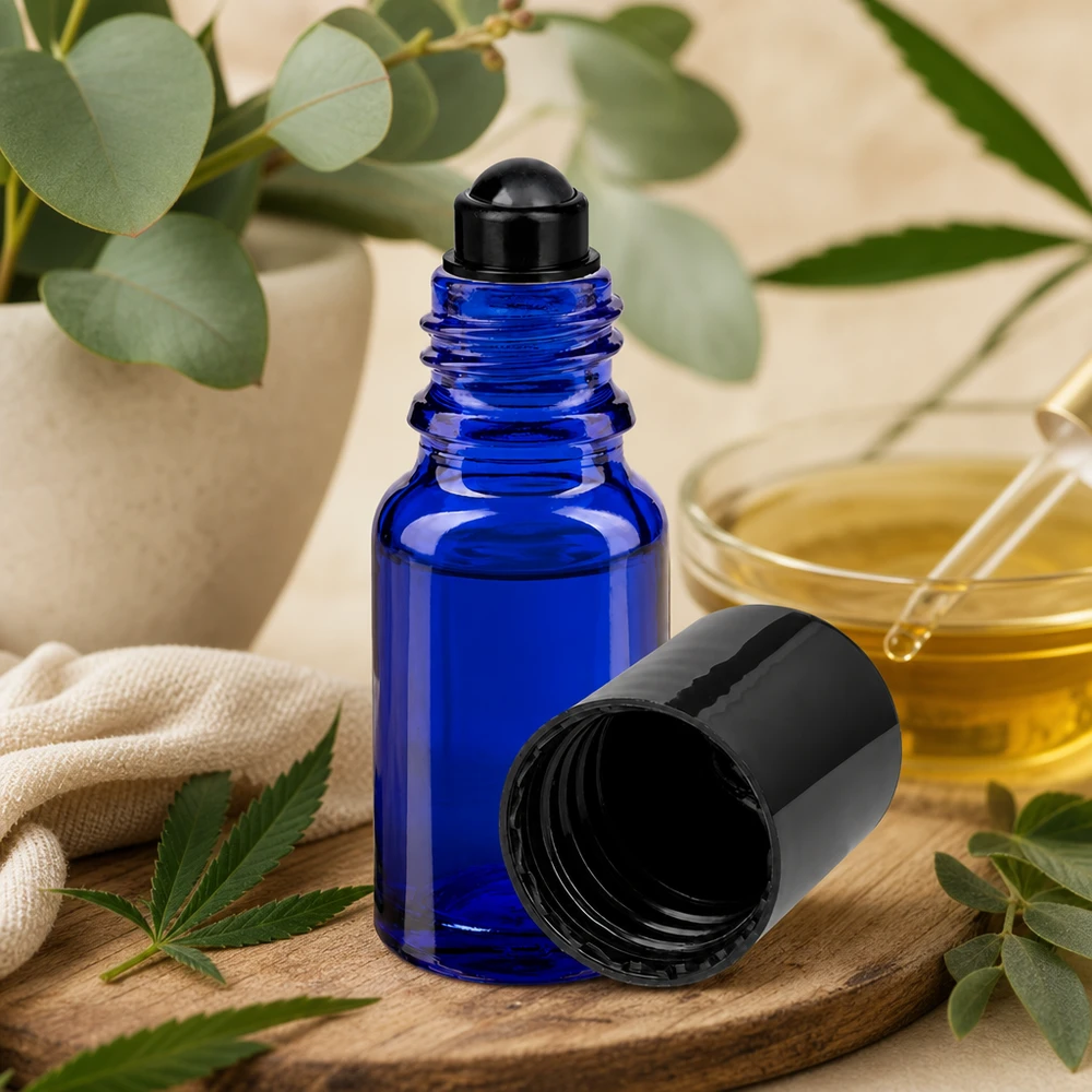 Apoteksflaska blå 10ml roll-on lock svart Blå 10 ml ApoGlas-roll-on-flaska med svart lock på en träbricka bredvid ett cannabisblad och en eukalyptus