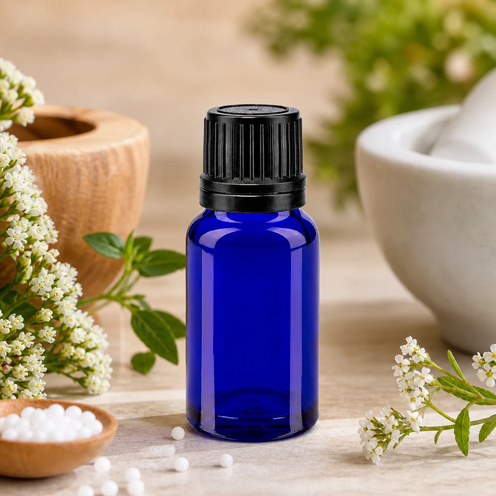 Blå 10 ml apoteksglasflaska med svart OV-lock mellan vita blommor och en mortel