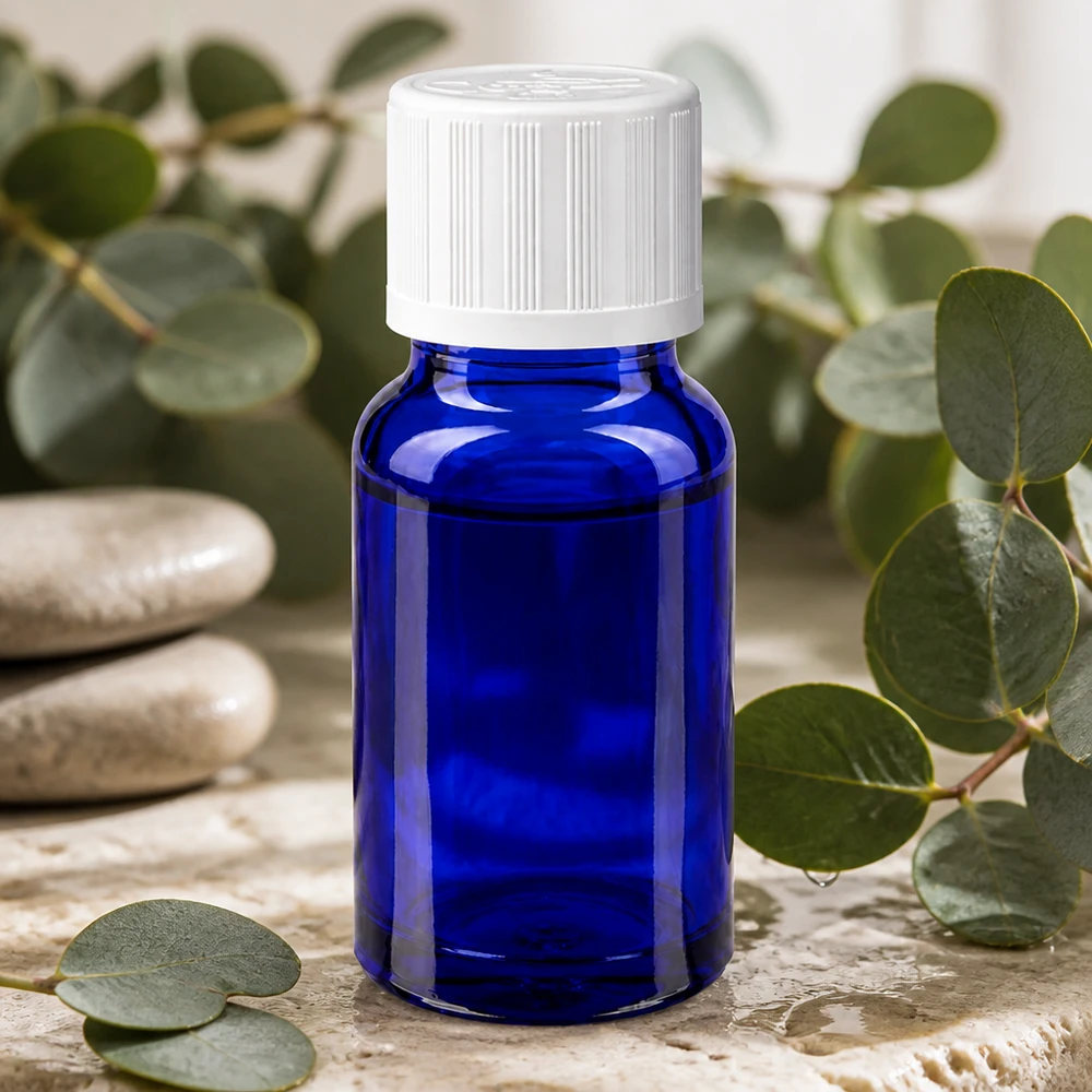 Apoteksflaska blå 10ml skruvkork vit barnsäker standard Blå 10 ml apoteksflaska med vitt barnsäkert lock bland eukalyptusgrenar