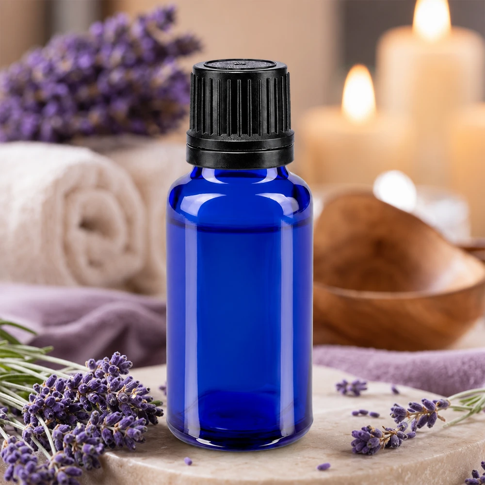 Apoteksflaska blå 20ml skruvkork svart hällring tät förslutning Blå glasflaska på 20 ml med svart droppkork, omgiven av lavendelblommor och ljus