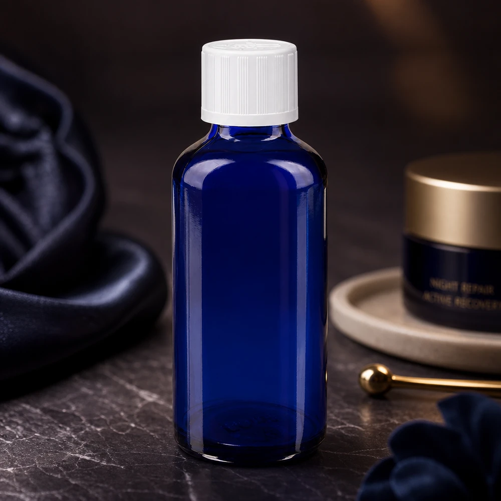 Apoteksflaska blå 50ml skruvkork vit barnsäker standard Koboltblå apotekarflaska på 50 ml med vitt barnsäkert lock mot en mörk marmorbakgrund