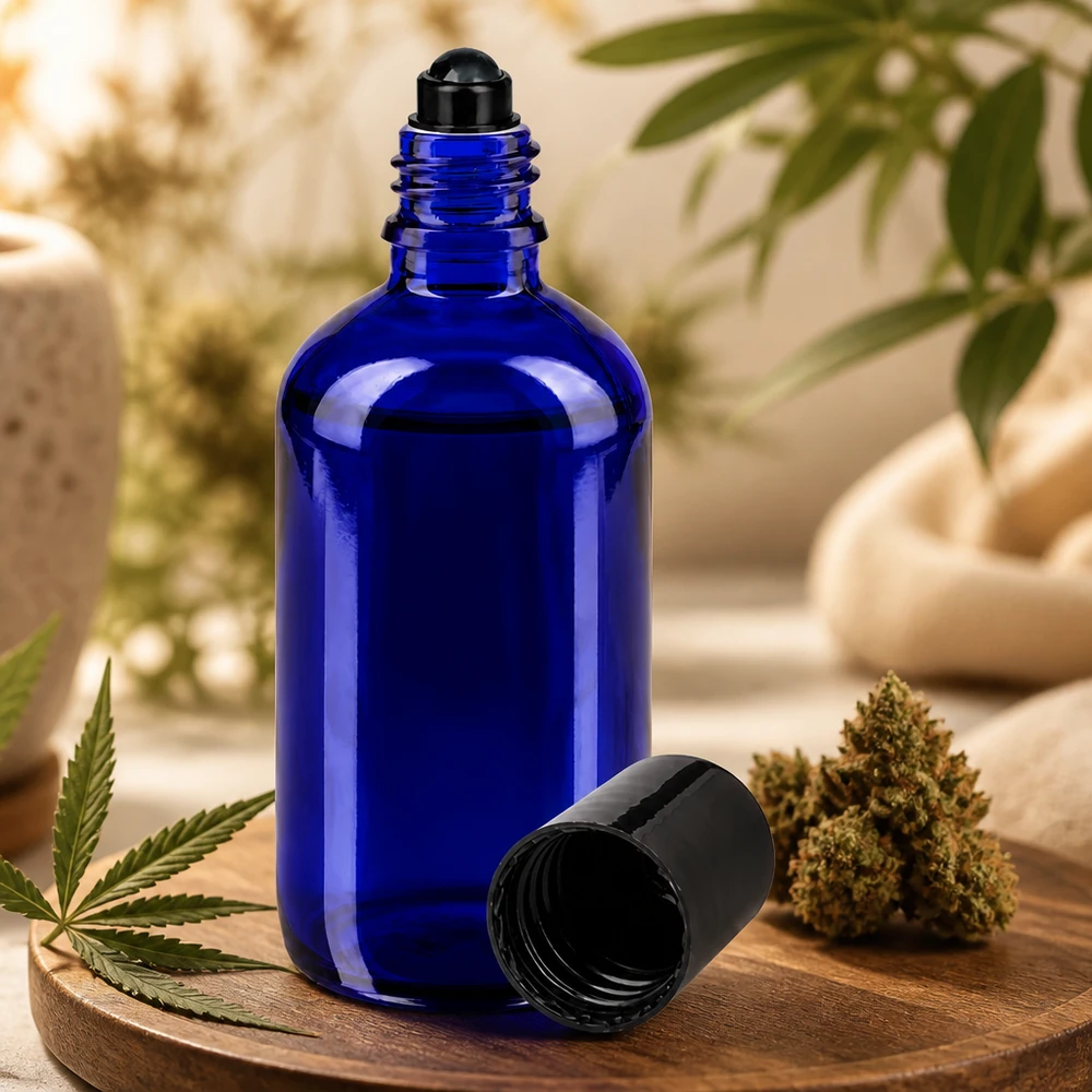 Apoteksflaska blå 100ml roll-on lock svart Blå 100 ml roll-on-flaska av apotekerglas bredvid en cannabisblomma och ett hampablad på en träbricka