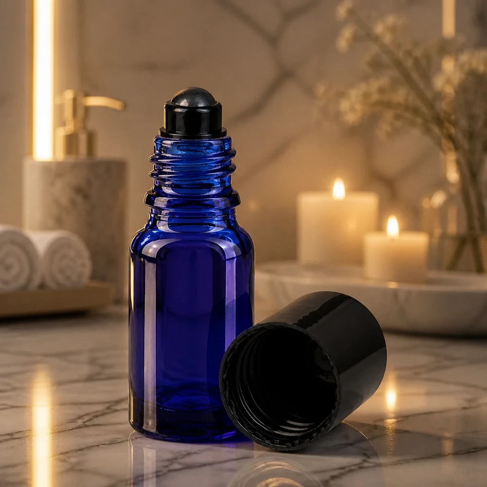 Apoteksflaska blå 10ml roll-on lock svart En koboltblå 10 ml roll-on-flaska med svart rullkula i stämningsfullt stearinljus på marmor