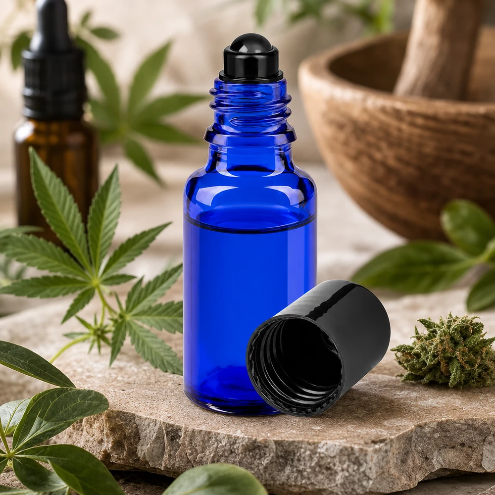 En liten 20 ml roll-on-flaska av blått apotekerglas bredvid en cannabisväxt och en mortel