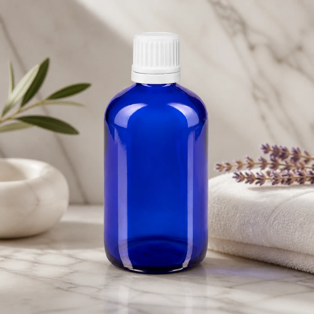 Apoteksflaska blå 100ml droppflaska 1.2mm vit barnsäker förslutning Blå 100 ml droppflaska av apotekerglas med vit OV-kork på marmorunderlägg