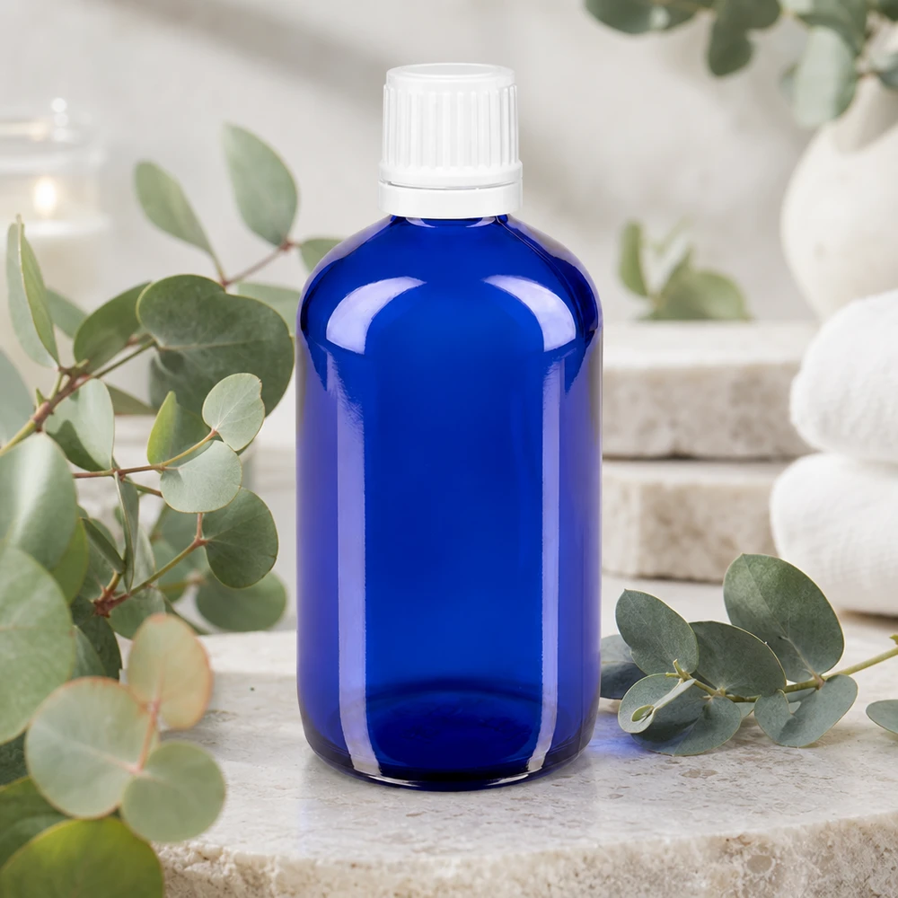 Koboltblå apotekarflaska, 100 ml, med vitt säkerhetslock på natursten med eukalyptusgrenar