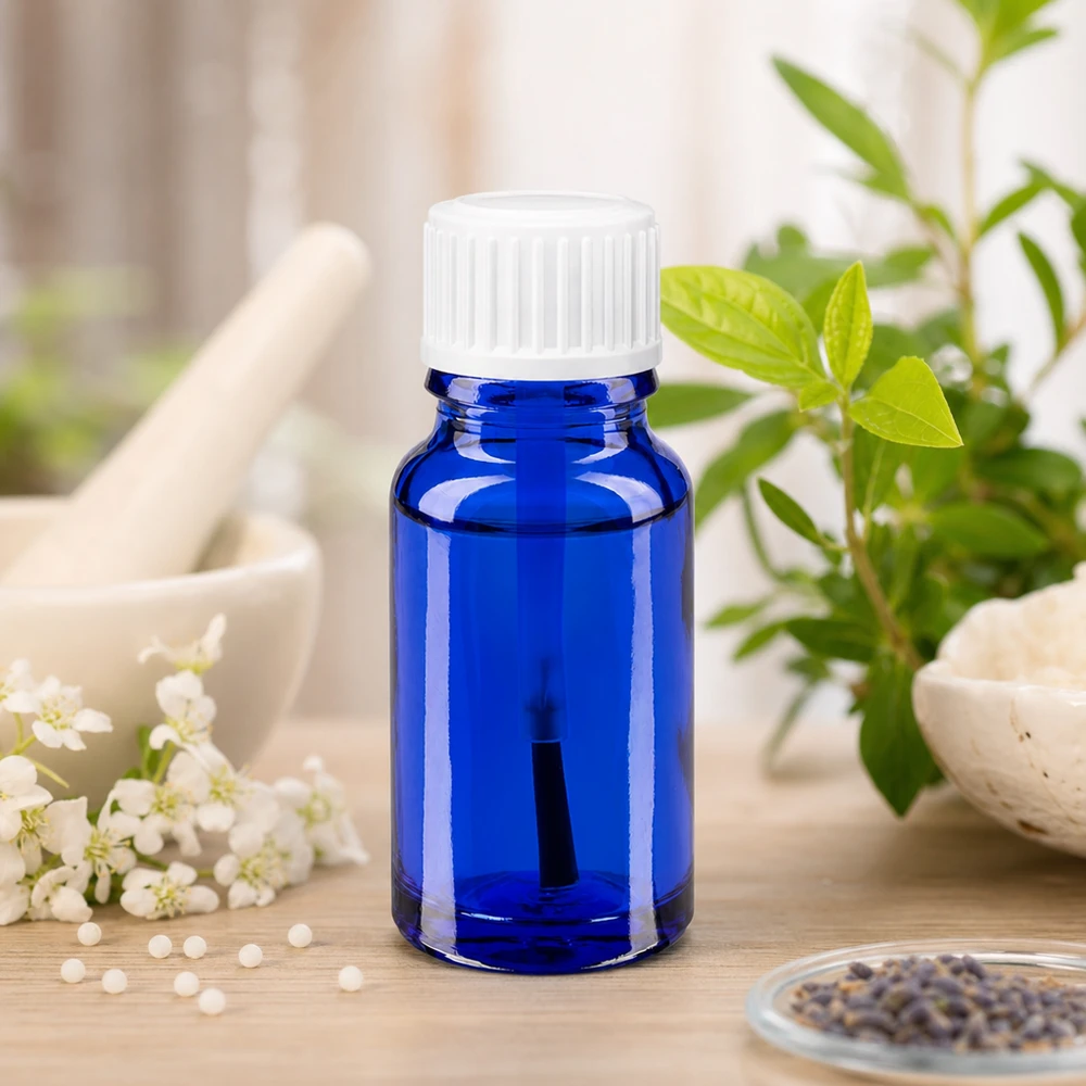 Apoteksflaska blå 10ml skruvlock vit borste Blå glasflaska på 10 ml med vitt lock bredvid färska örter och blommor i en naturlig miljö