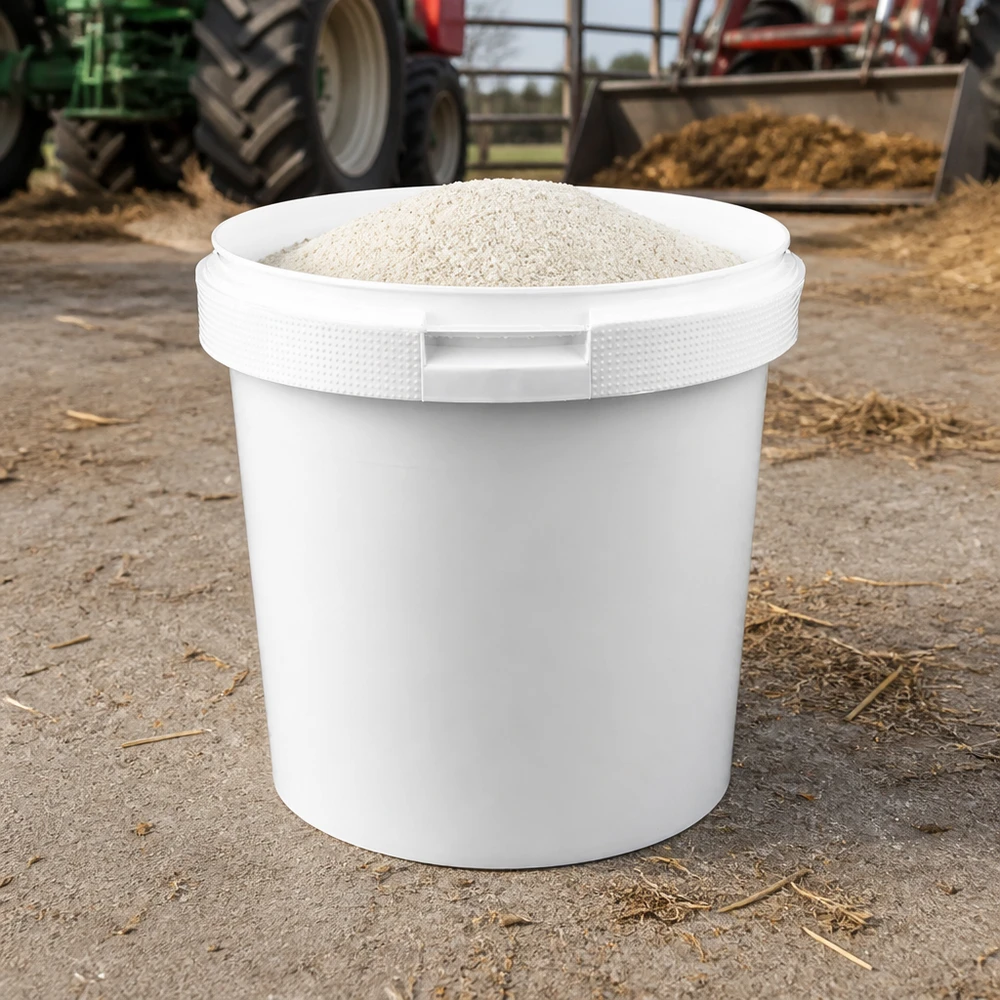 2,5-liters hink av vit polypropenplast utan lock Vit PP-hink på 2,5 liter fylld med pulver på en bondgård framför en traktor och hö