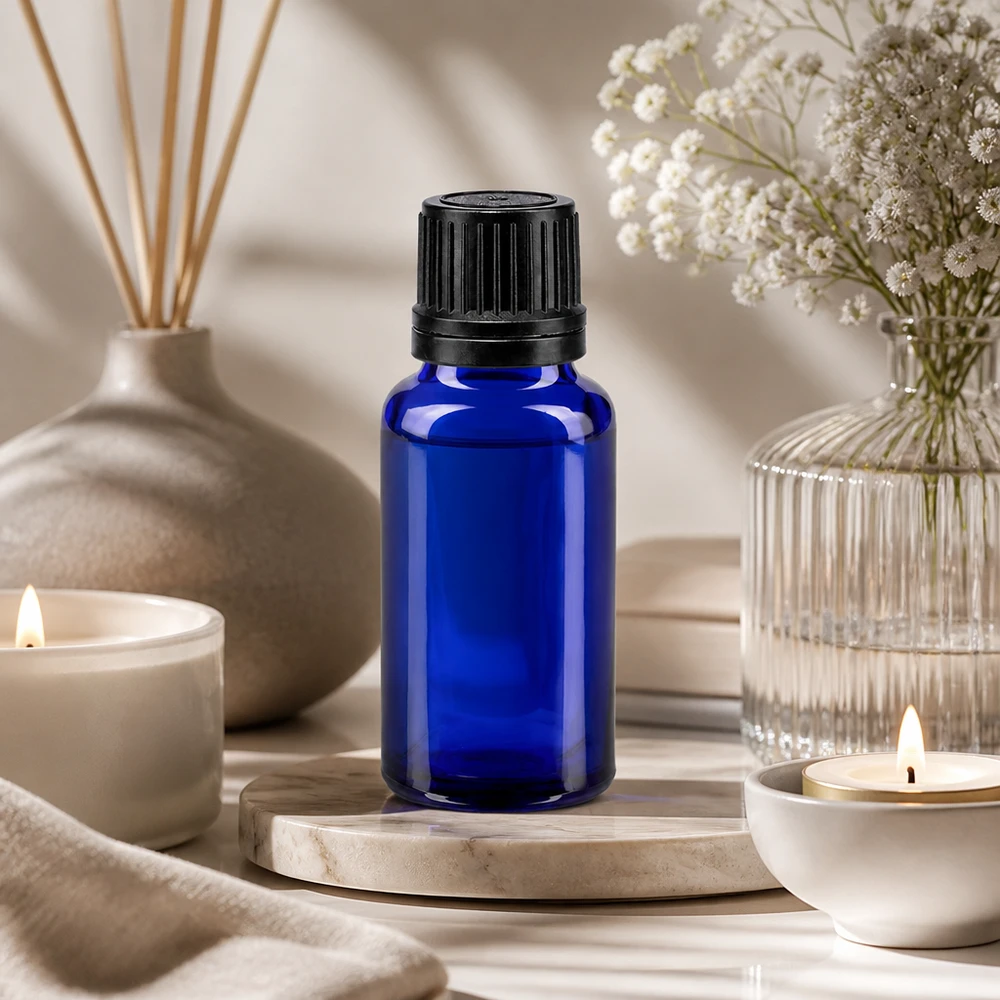 Apoteksflaska blå 20ml skruvkork svart hällring tät förslutning En 20 ml blå glasflaska med OV-lock på en marmorsockel i en avslappnad wellness-atmosfär