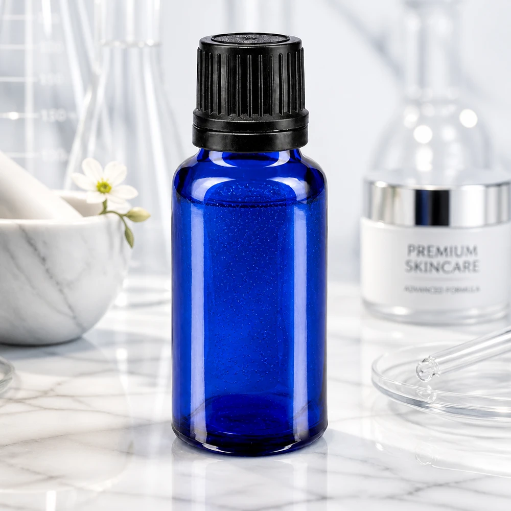 Apoteksflaska blå 20ml dropplock hällring 1mm svart manipuleringssäkert lock Blå glasflaska på 20 ml med svart skruvlock framför laboratorieglas på en marmorbakgrund