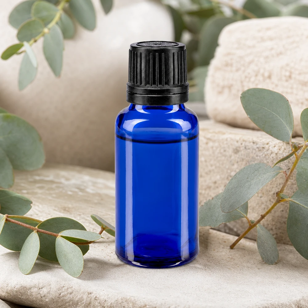 Koboltblå 20 ml apotekerglasflaska med 1 mm droppinsats bland eukalyptusgrenar på natursten