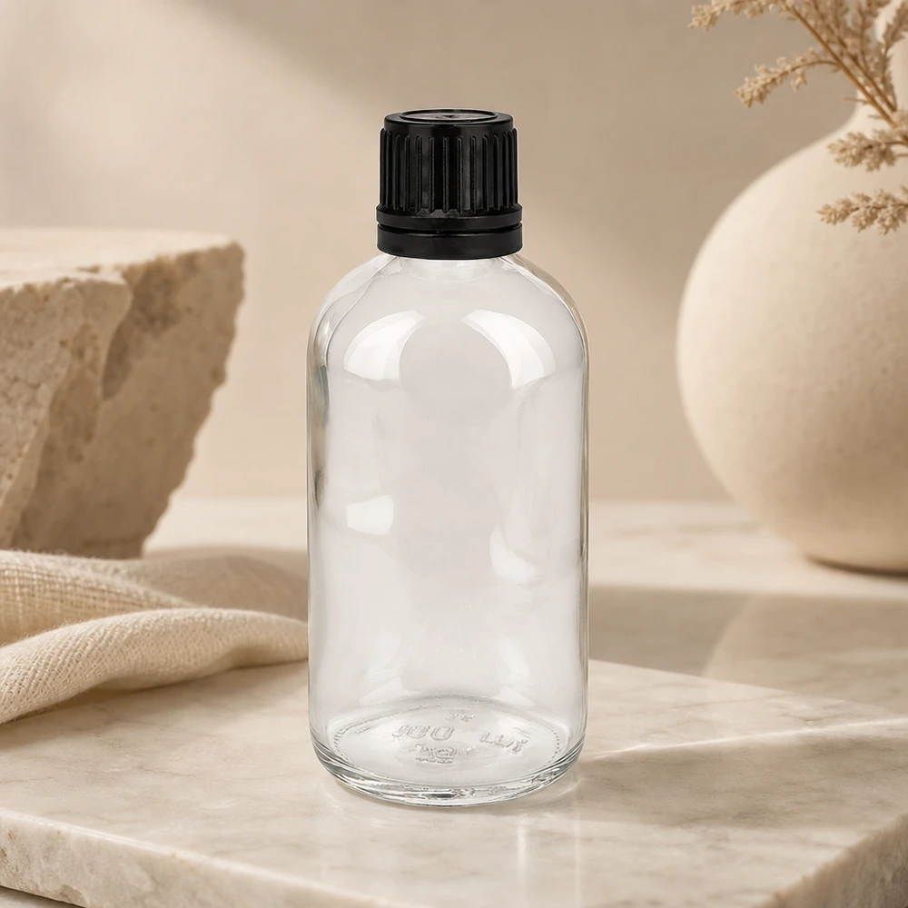 Cylindrisk 100 ml-flaska i klart glas med räfflad svart lock på marmorunderlag