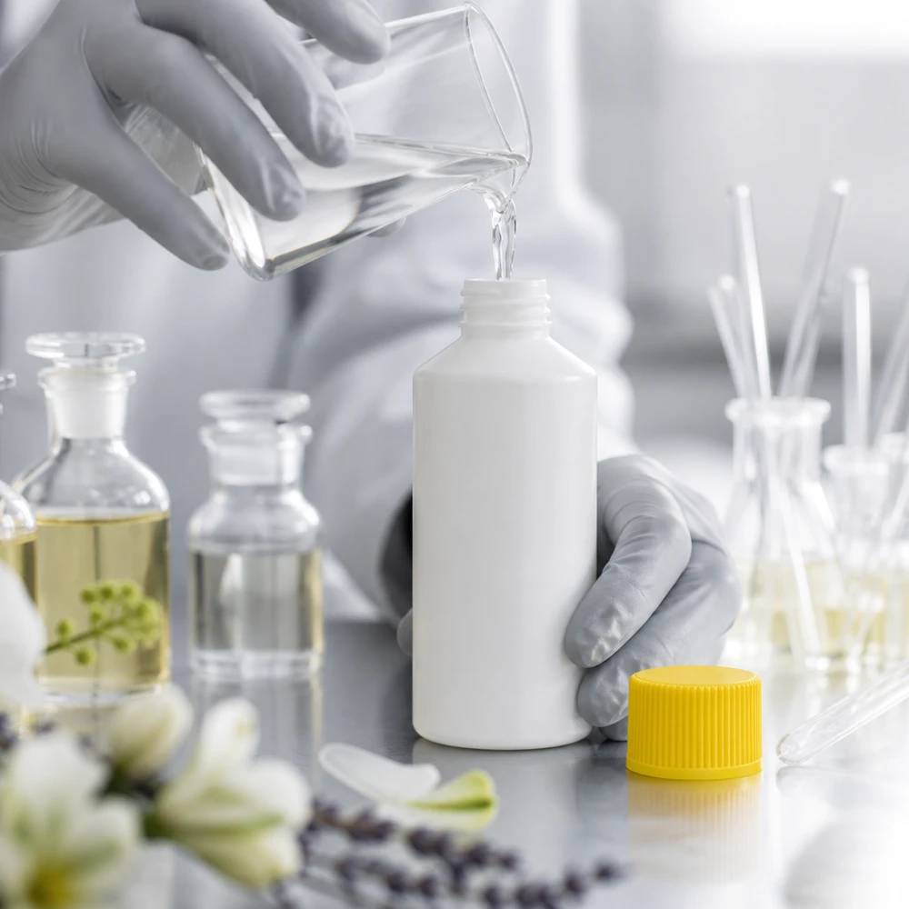 Apoteksflaska HDPE 50ml vit, med gult skruvlock Påfyllning av en vit HDPE-flaska på 50 ml med klar vätska från ett glasbägare i laboratoriet
