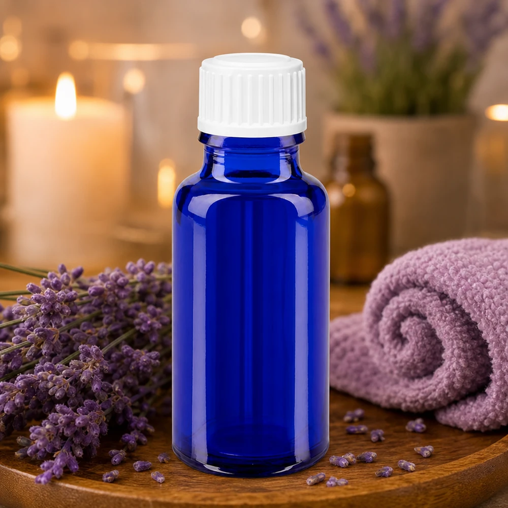 Blå glasflaska på 20 ml med vitt lock, omgiven av lavendelblommor på en träbricka