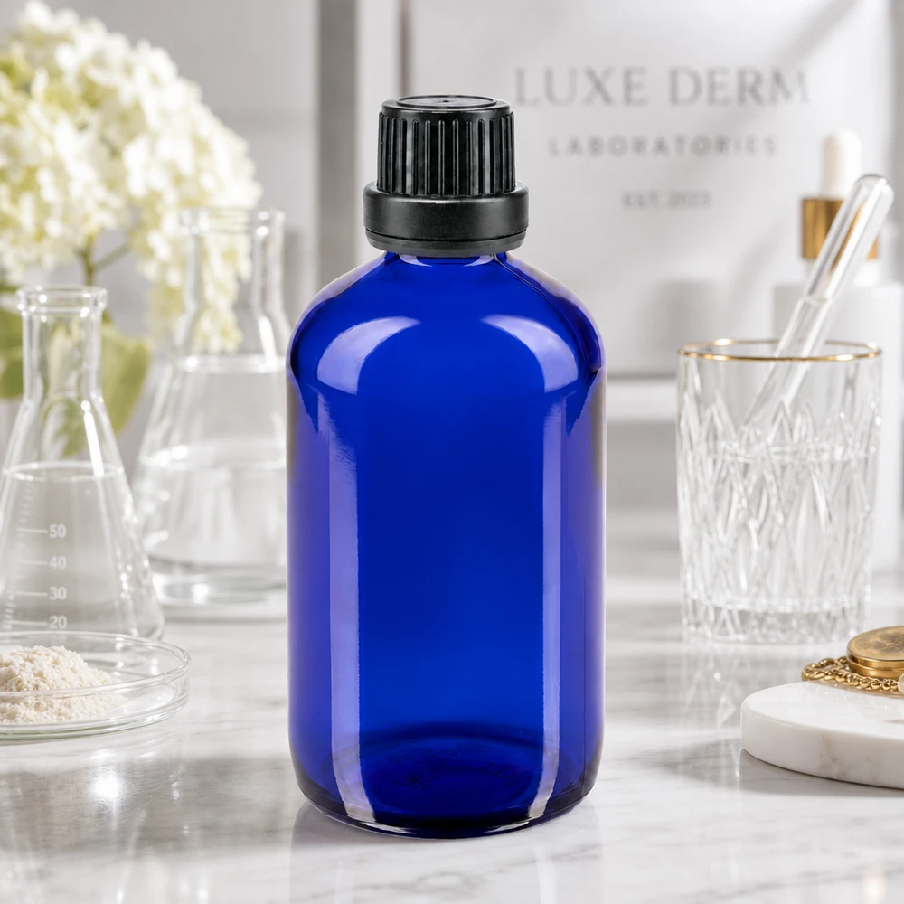 Apoteksflaska blå 100ml skruvkork svart säkerhetsförslutning Blå glasflaska på 100 ml med svart originalförslutning framför bakgrunden från Luxe Derm Laboratorien