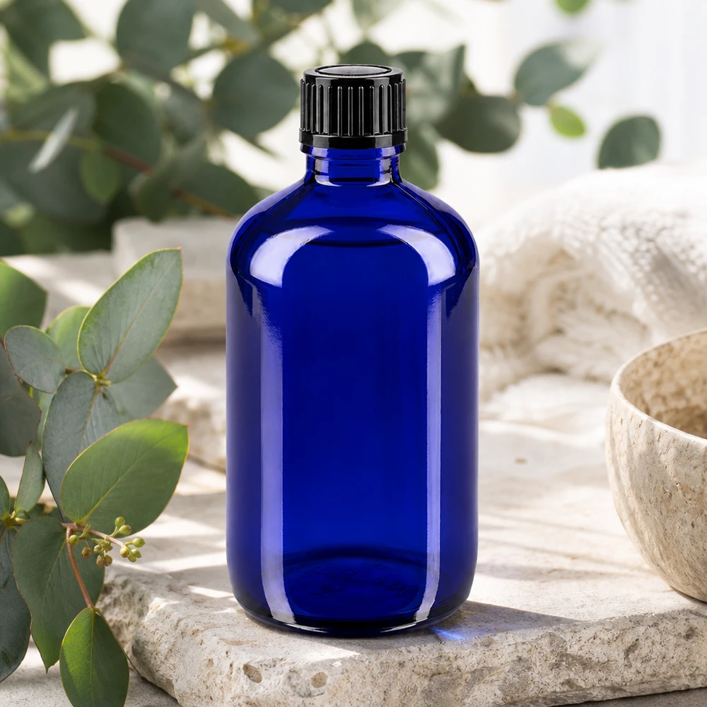Apoteksflaska blå 100ml skruvkork svart standard Blå 100 ml apoteksflaska med svart standardlock på natursten med eukalyptus