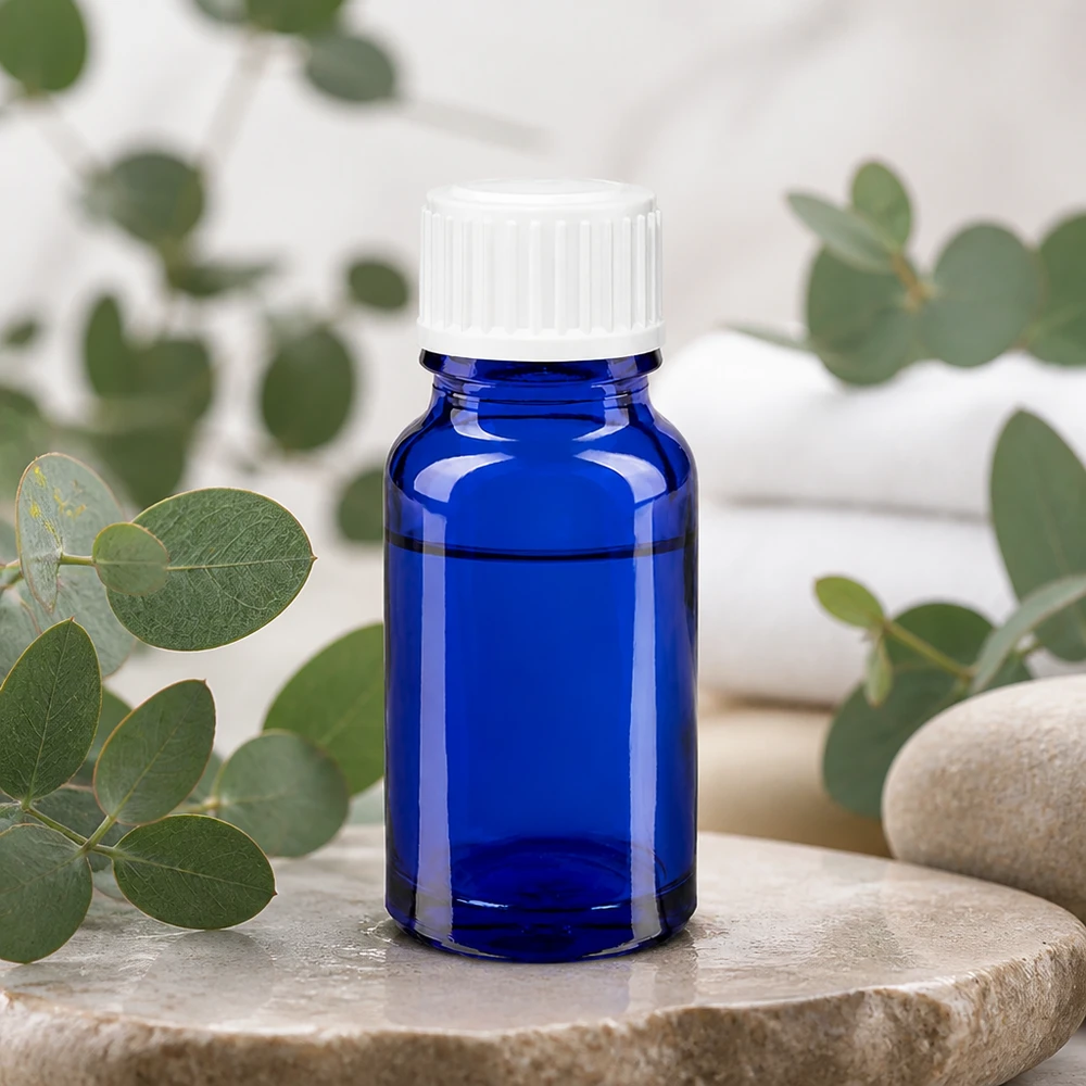 Apoteksflaska blå 10ml skruvkork vit standard Koboltblå 10 ml apoteksflaska med vit droppkork på natursten med eukalyptus