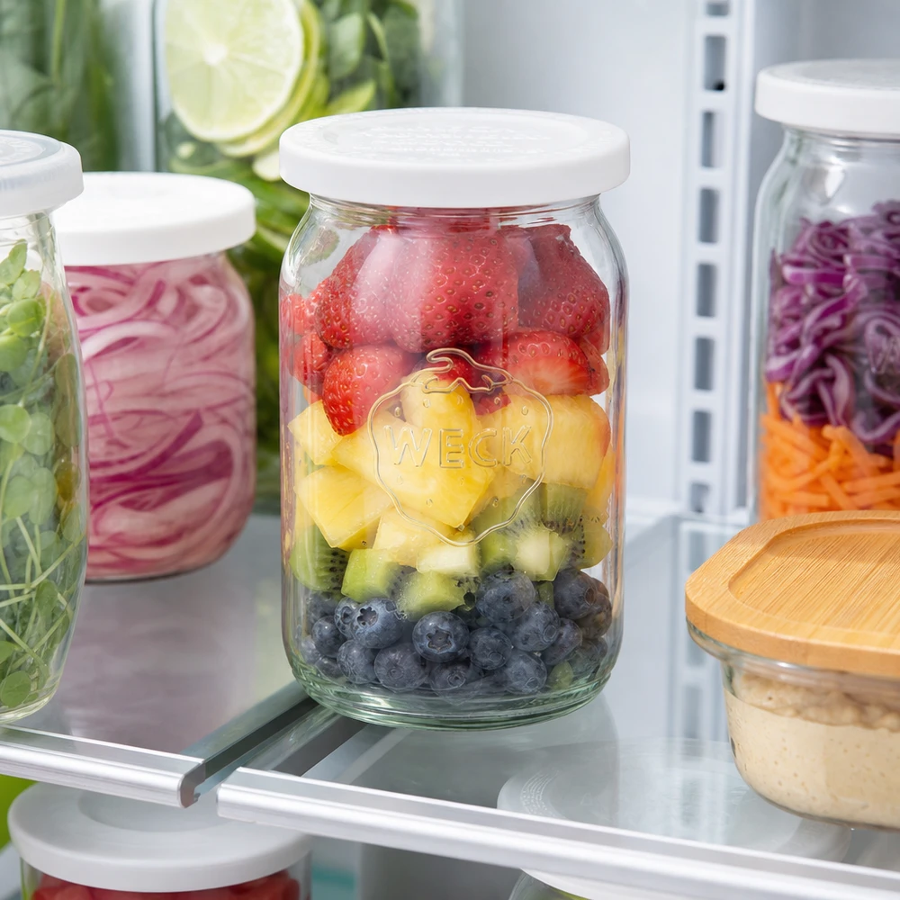 145 ml cylinderburk med lock för färskhet. WECK RR40 WECK RR40 cylindrisk burk 145ml fylld med frukt i kylskåpet för måltidsförberedelser med bär och kiwi