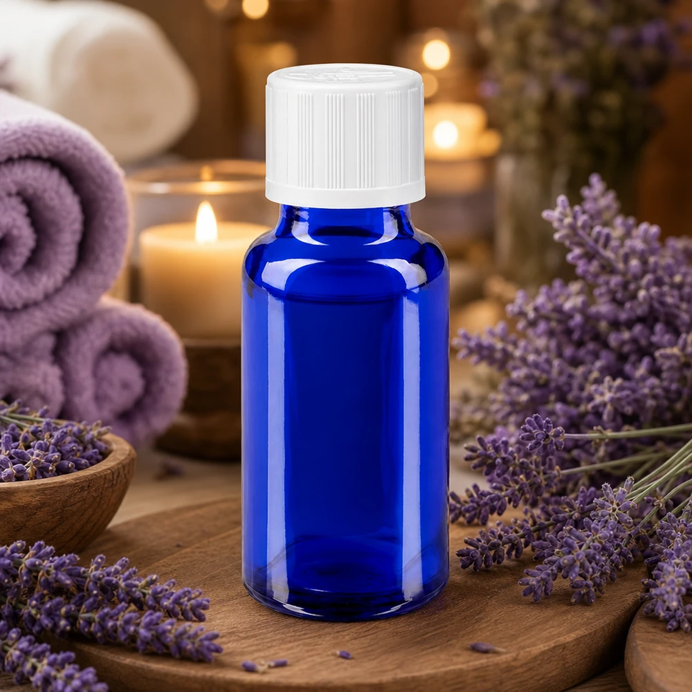 Blå glasflaska på 20 ml med vitt skruvlock bland lavendelblommor och ljus