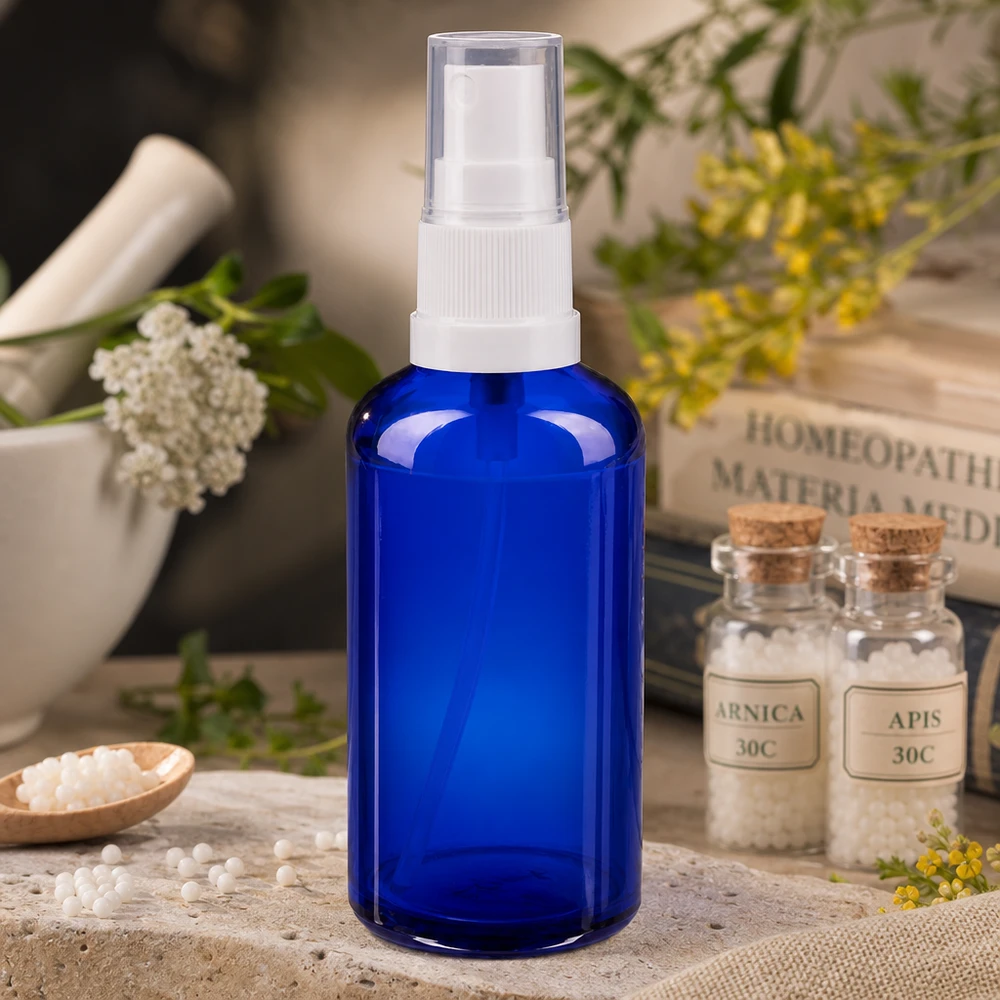 Apoteksflaska blå 50ml spray topp vit 50 ml blå apoteksglasflaska med sprayhuvud och vit pump bredvid homeopatiska globuli